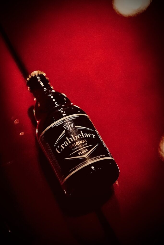 Crabbelaer Original Blond fles liggend op een glanzend rood oppervlak – Belgisch blond bier