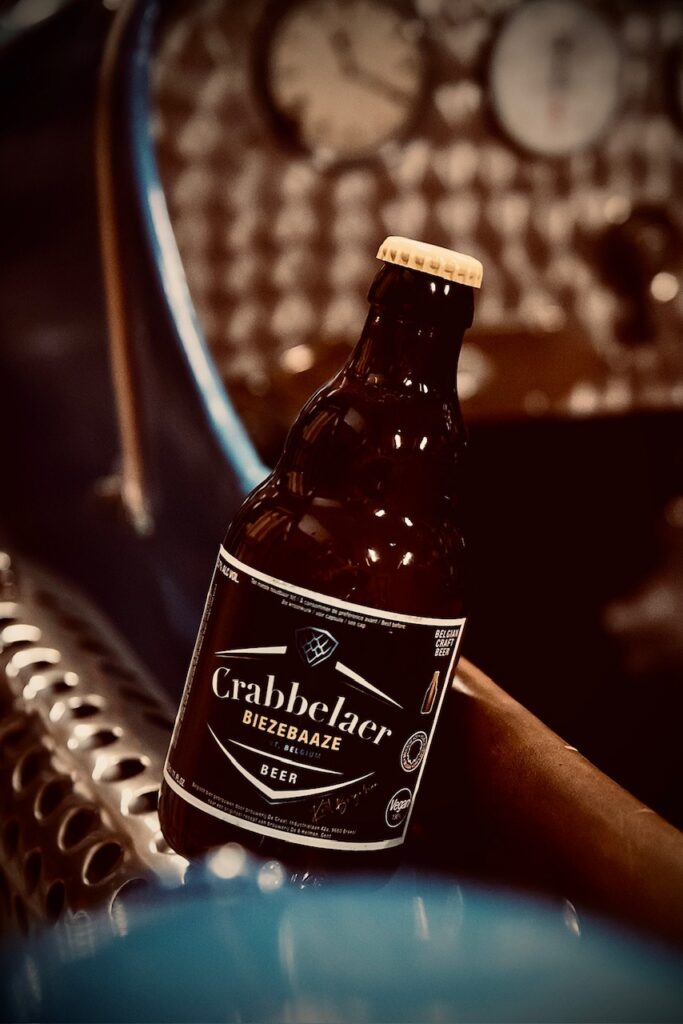 Crabbelaer Biezebaaze fles op de verchroomde zijuitlaat van een lichtblauwe oldtimer met interieurdetails – Belgisch speciaalbier